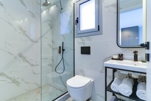 A modern bathroom with a glass-enclosed shower, a white toilet, and a sink with a mirror above it. - AboV Athens (Athens)