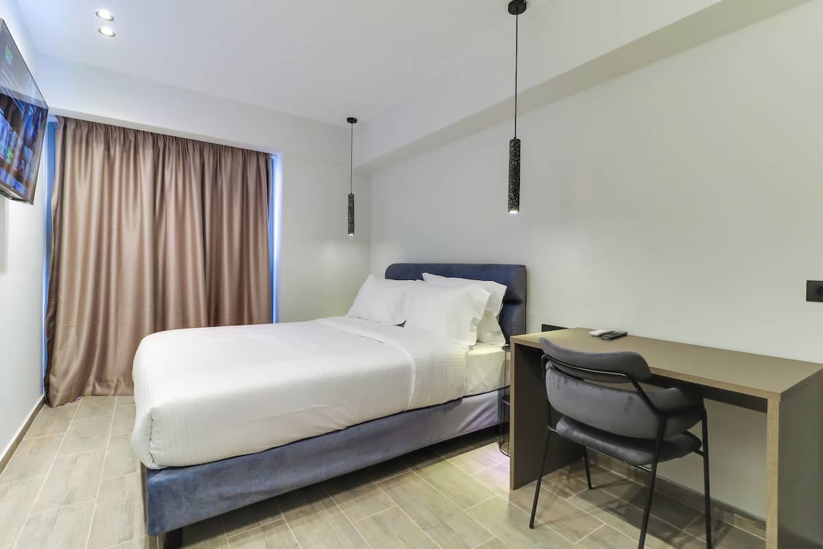 Ein modernes Hotelzimmer mit Bett, Schreibtisch und Stuhl.