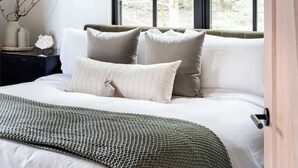 A bedroom with a large window, a bed with white bedding, and a dark nightstand with a lamp. - The Barn Villa (Healdsburg)
