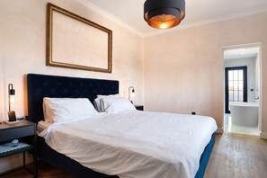 A neatly made bed with white linens, a dark headboard, and a bedside table with a lamp. - Exclusive Villa for Groups in Chiclana de la Frontera (Chiclana de la Frontera)