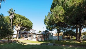 Un bâtiment doté d’un patio couvert, entouré d’arbres et sous un ciel dégagé.