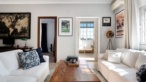 Un salon avec une table basse en bois, des canapés blancs et un grand tableau représentant une carte du monde.