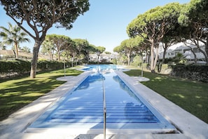 A swimming pool with a clear blue water feature, surrounded by well-maintained grass and trees.