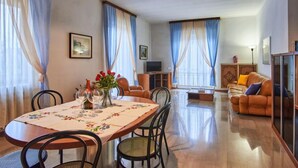 A spacious living area with a dining table set for four, a sofa, and a television in the background. - Massimo by Interhome (Dervio)