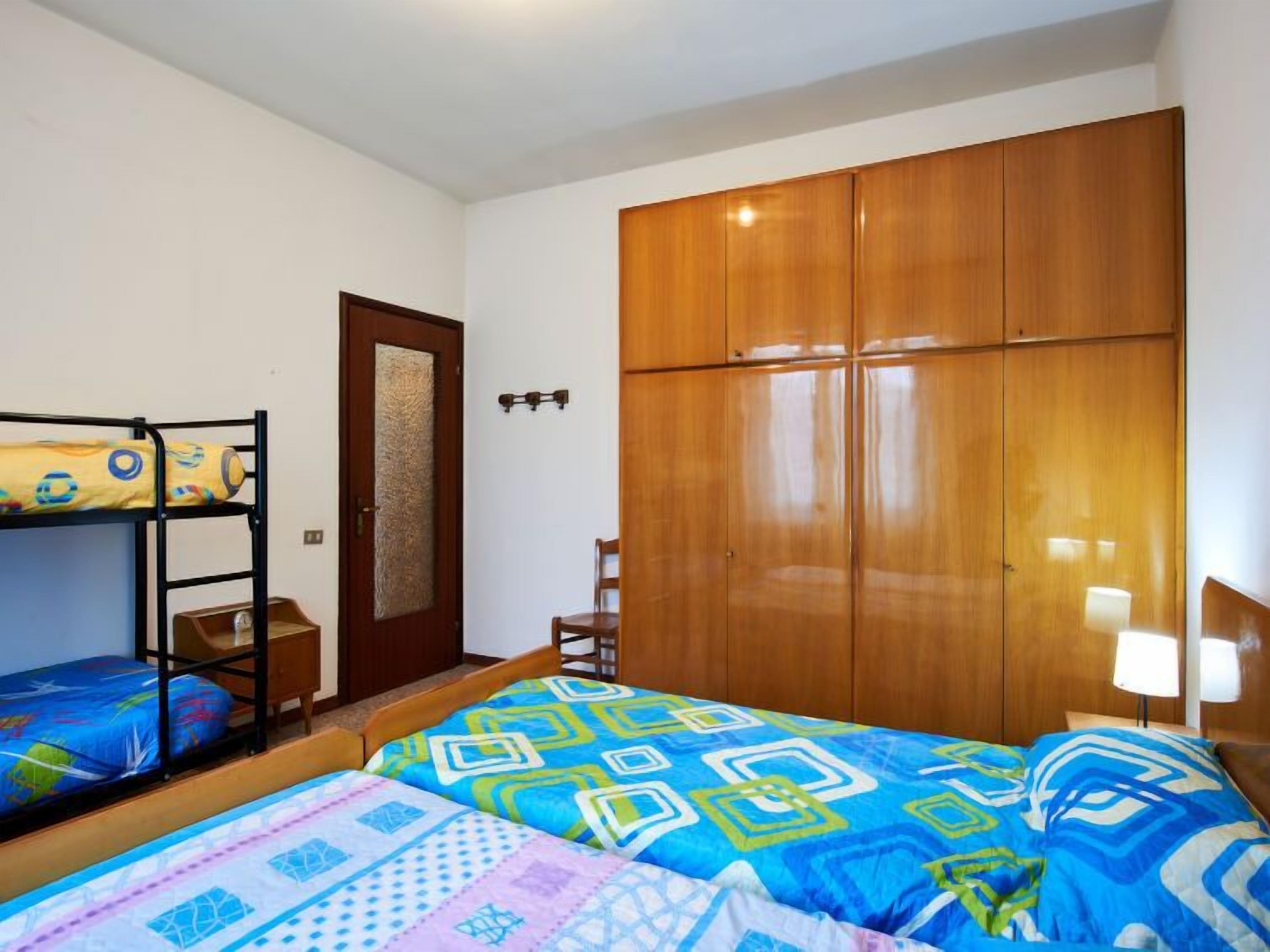Um quarto com beliches, um guarda-roupa de madeira e uma pequena mesa de cabeceira.