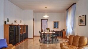 A spacious living room with a leather sofa, a dining table with chairs, and a cabinet with glass doors. - Massimo by Interhome (Dervio)