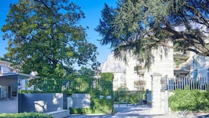 A modern building with a stone facade, a gated entrance, and lush greenery. - Promessi Sposi by Interhome (Lecco)