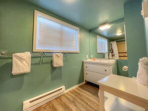 A bathroom with a green wall, a white sink, and a mirror.