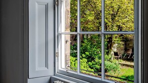 A room with a large window, a door, and a view of greenery outside. - Drake Suite - City Centre 1 Bed Apartment (Edinburgh)