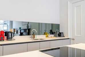 Une cuisine moderne équipée d’un lave-vaisselle encastré, d’un évier et d’une machine à café.
