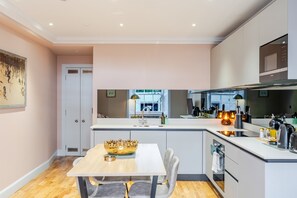 Une cuisine moderne dotée d’un îlot central, d’appareils électroménagers intégrés et offrant une vue sur l’extérieur.