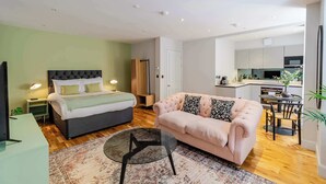 Een modern appartement met een bed, bank, eettafel en keukenhoek.