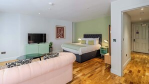 Een moderne slaapkamer met een bed, nachtkastje, lamp en een televisie op een kast.