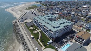 A coastal hotel with a pool, parking, and a view of the beach.