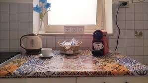 A kitchen with a coffee maker, a cup, and a basket of bread on a tiled countertop. - Comfortable apartment in central area (Bari)