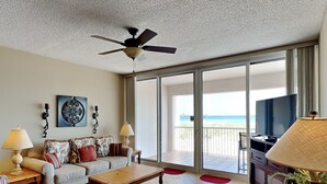 A spacious living room with a ceiling fan, a sofa set, a coffee table, and a television.