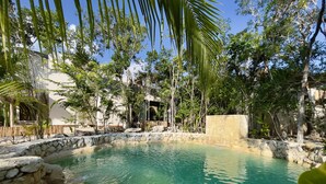 Una piscina nítida envoltada de murs de pedra i vegetació tropical.