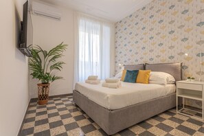 Ein Hotelzimmer mit Bett, einer Topfpflanze, einem Flachbildfernseher und einem Schachbrettfußboden.