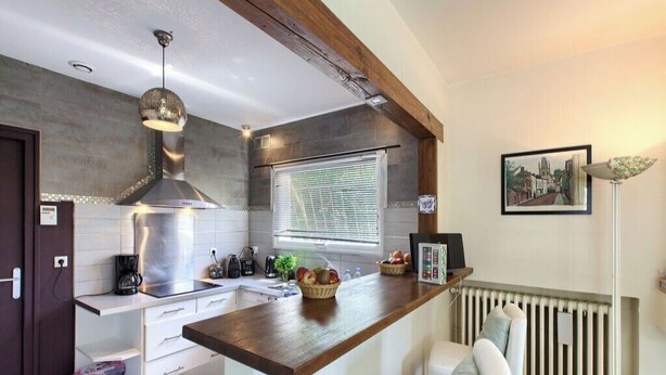 A modern kitchen with a wooden countertop, a built-in stove, and a window with blinds. - Villa des Doudoux (Andernos-les-Bains)