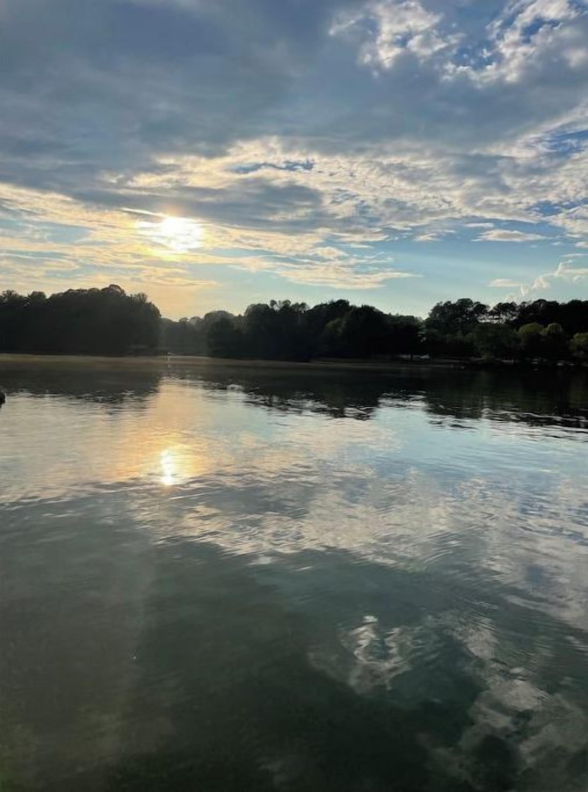 Un lago tranquilo que refleja claramente el cielo y los árboles.