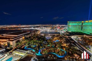 Un complexe hôtelier doté de plusieurs piscines, d’un grand hôtel et offrant une vue sur la ville la nuit.