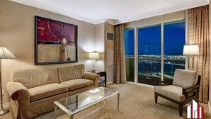 Habitación de hotel con sofá, sillón y una mesita de centro de vidrio. Amplia ventana con vista a la ciudad.