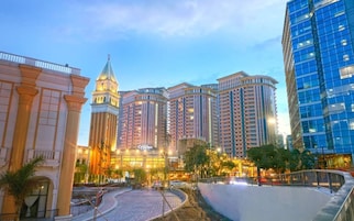 Un hotel con un atrio central, varios pisos y un edificio moderno de cristal a la derecha.