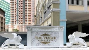 Un hall d’entrée en marbre, sur lequel on peut lire l’inscription « The Venice Residences », flanqué de deux statues de lions blancs.