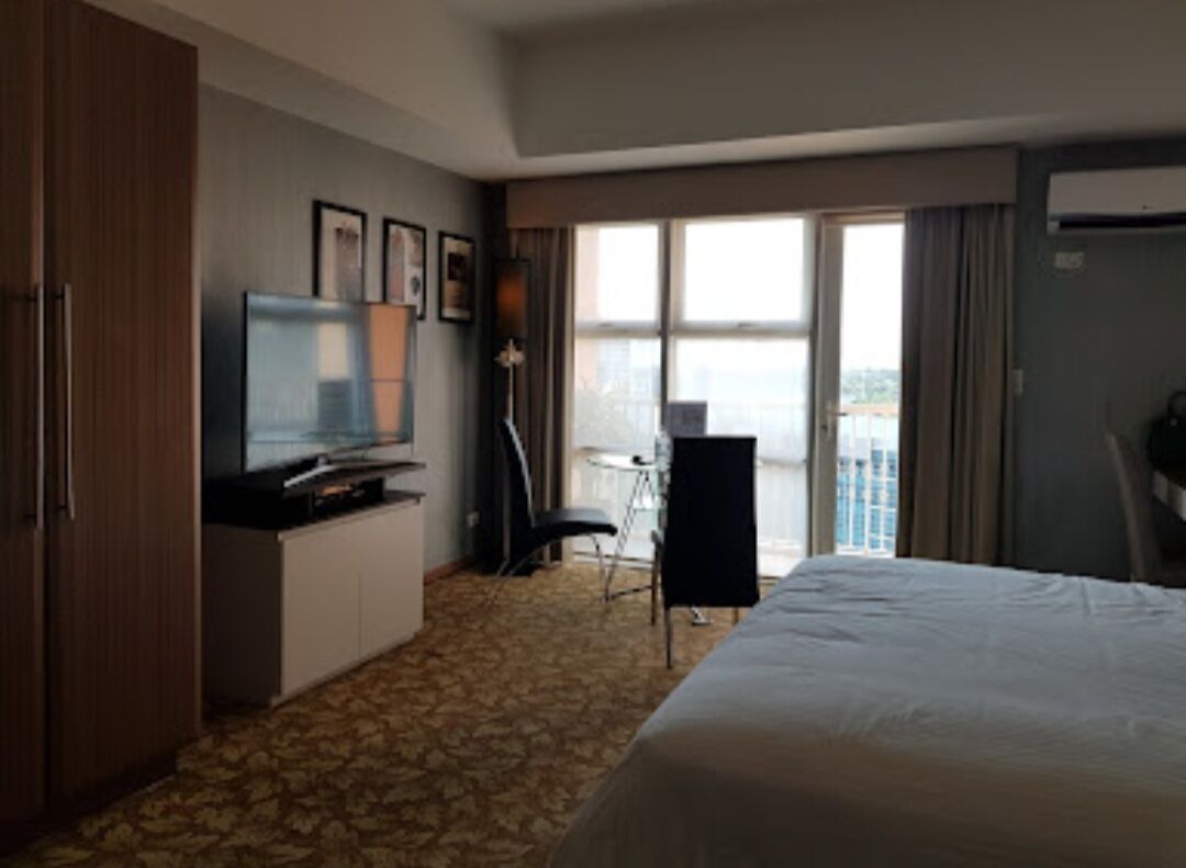 A hotel room with a bed, a television, a desk, and a chair.