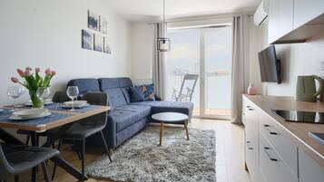 A modern living room with a sofa, dining table, and a view of the outdoors.