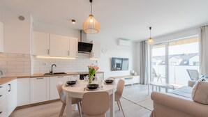 A modern kitchen with white cabinets, a round dining table, and a large window overlooking a balcony.