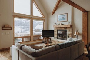 A cozy living room with a fireplace, a large window, and a television.