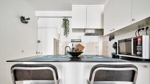 A modern kitchen with white cabinets, a black countertop, a microwave, and a sink. - Nice Apartment at 10 min From Bastille (Paris)