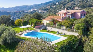 Una villa con piscina, rodeada de exuberante vegetación y vistas al campo.