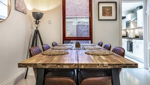 Un comedor con una mesa de madera, sillas de cuero y vista a la cocina por una ventana.