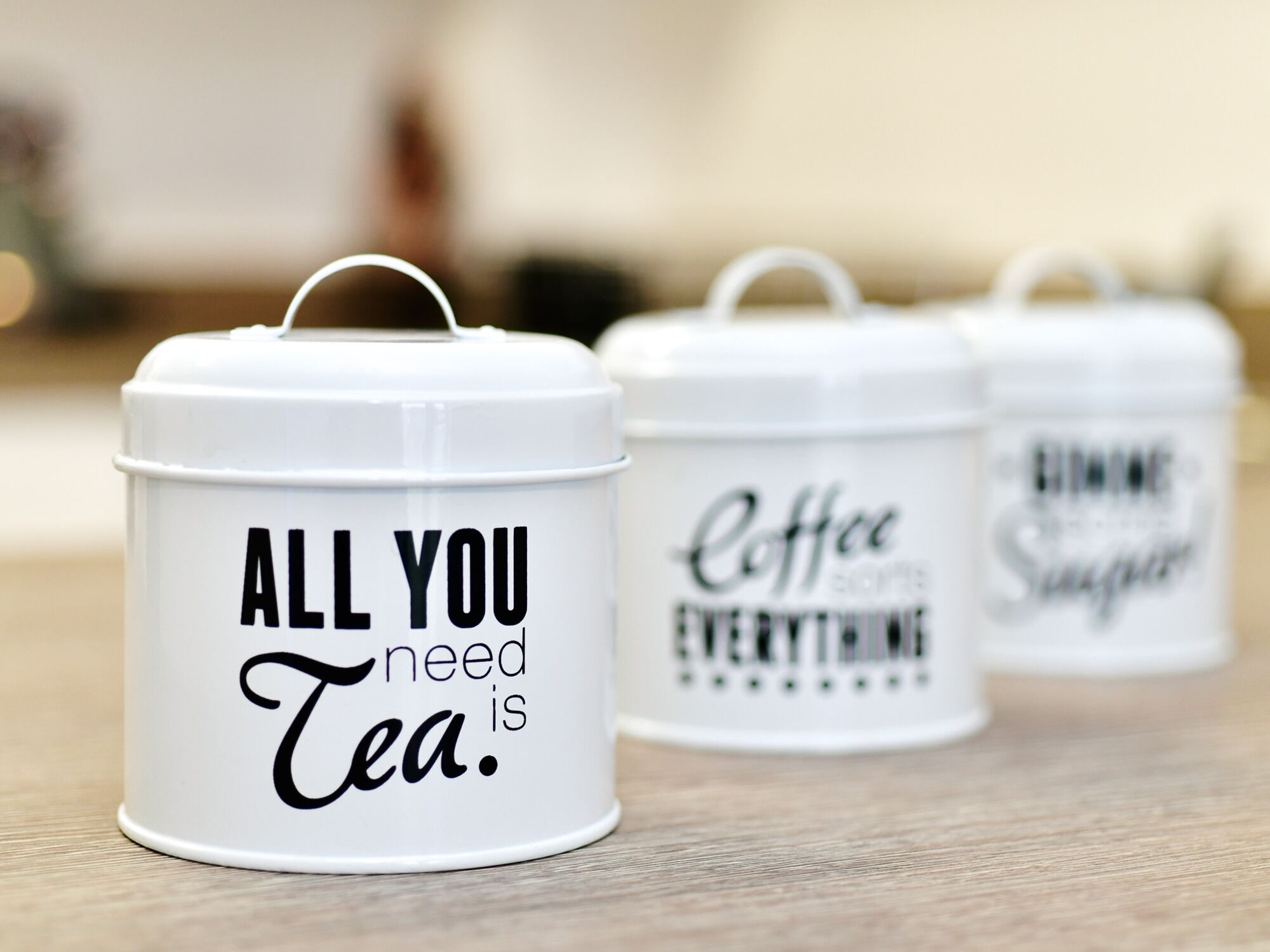 Three white containers with handles, each with different text: "ALL YOU need Tea.", "Coffee is everything.", and "TIME is Sugar."