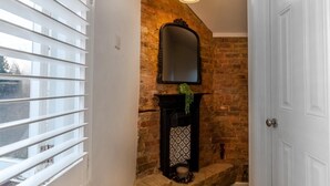 Un baño con pared de ladrillo, chimenea y puerta blanca.
