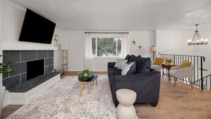 Een moderne woonkamer met een open haard, een bank, een salontafel en een trap.