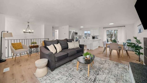 Een moderne woonkamer met een donkere bank, een klein rond salontafeltje en een eethoek met een tafel en stoelen.