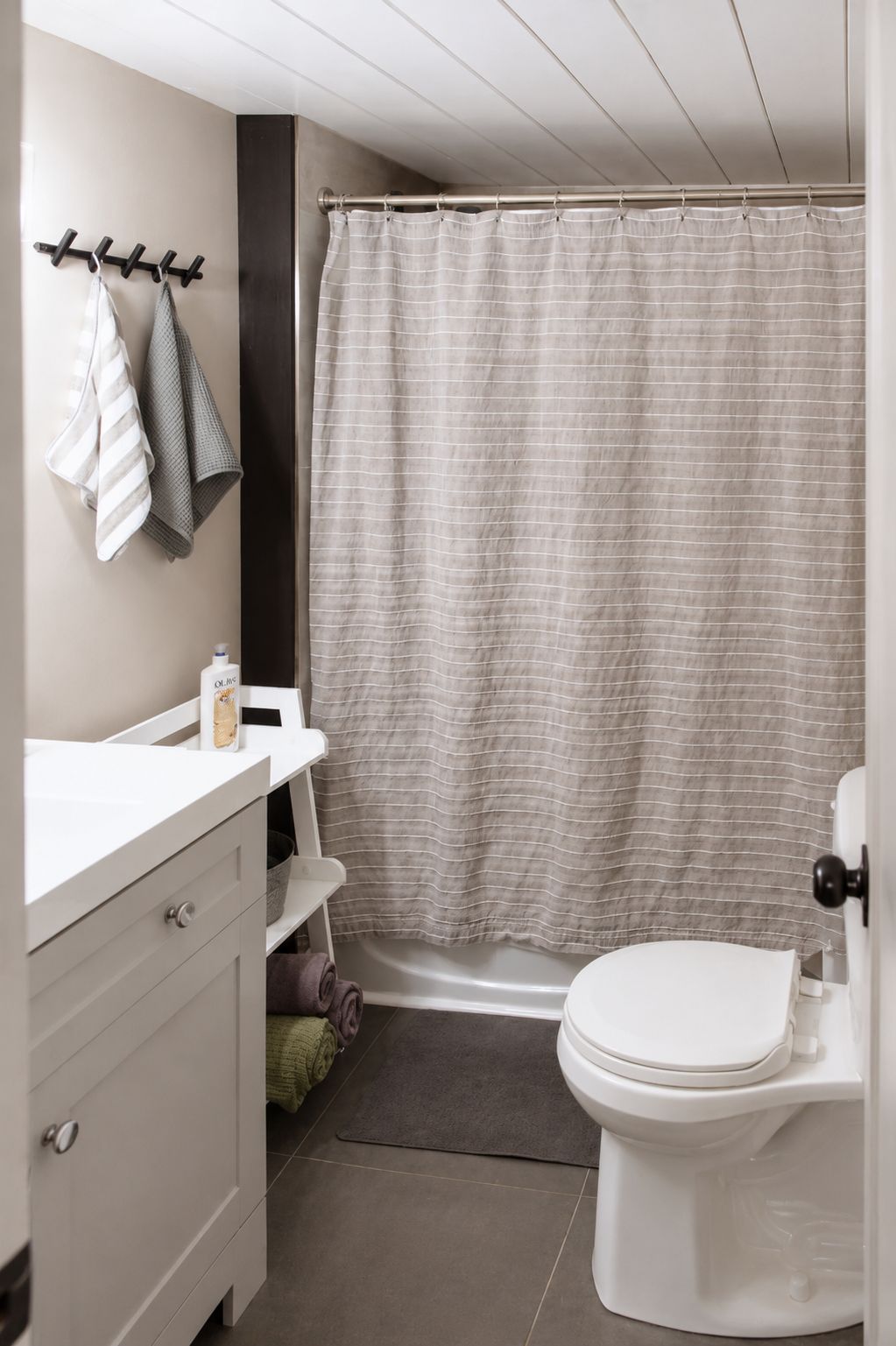 Une salle de bain équipée d’un rideau de douche, de toilettes, d’un lavabo avec un distributeur de savon et d’un porte-serviettes avec des serviettes.