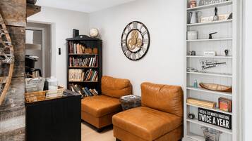 Un salón con dos sofás de cuero, una estantería, un reloj decorativo y un mueble blanco con varios objetos.