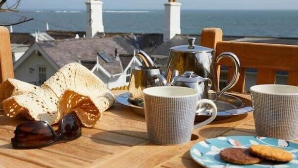 A breakfast setup with bread, tea, and a view of the sea.