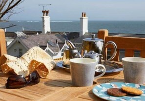 En frukostuppsättning med bröd, te och utsikt över havet.