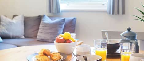 A breakfast setup with croissants, fruit, coffee, and orange juice on a wooden table.