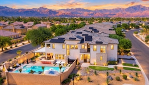 A modern two-story house with a swimming pool, surrounded by a landscaped garden and a view of mountains. - Ultimate Desert Getaway, Pool/Spa, 4k Game Room (Indio)