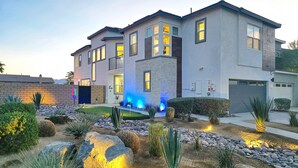 A modern two-story house with a landscaped garden featuring rocks, cacti, and a small water feature. - Ultimate Desert Getaway, Pool/Spa, 4k Game Room (Indio)