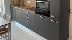 A modern kitchen with grey cabinets, a wooden countertop, a built-in oven, and a small window above the sink. - In the heart of Lake Como (Bellagio)