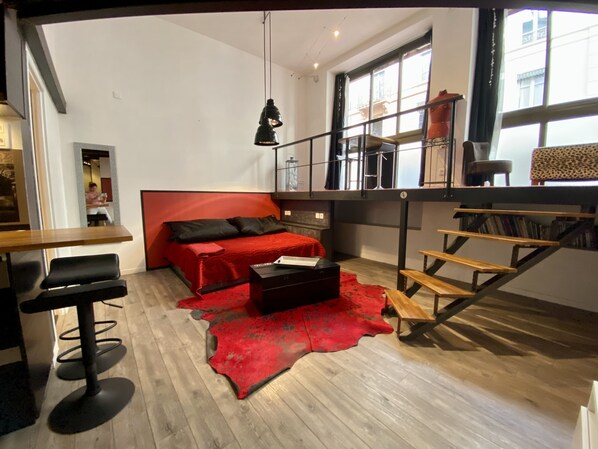 A modern living room with a red sofa, a wooden coffee table, and a staircase leading to an upper level.
