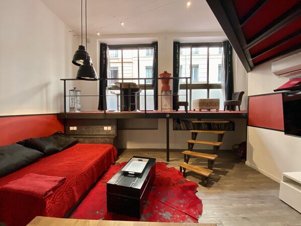 Un salon moderne avec un canapé rouge, une table basse et un escalier menant à un niveau supérieur.