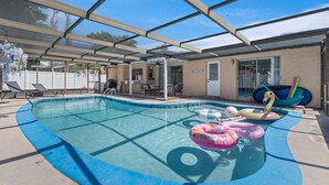 Une piscine extérieure couverte, dotée de chaises longues, de jeux gonflables et d’un espace patio.
